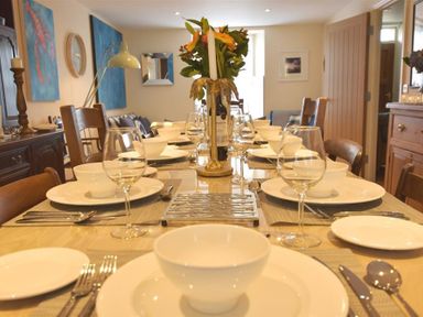 A dining table set with plates bowls wine glasses and cutlery in a dining room at Gwelfor Newport
