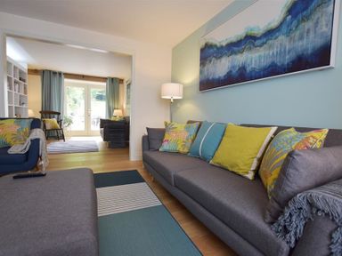 A living room with gray sofas colorful cushions a floor lamp and a blue abstract painting at Gwelfor Newport in Newport Pembrokeshire