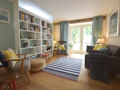 A living room with a bookshelf striped rug armchairs and sofa at Gwelfor Newport in Newport Pembrokeshire