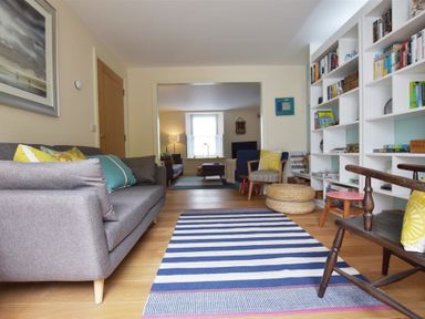 A living room with sofas, shelves with books, chairs, and a striped rug at Gwelfor Newport in Newport Pembrokeshire