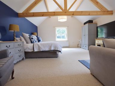 A bedroom with a bed bedside tables a window wooden ceiling beams and a television at Gwelfor Newport in Newport Pembrokeshire