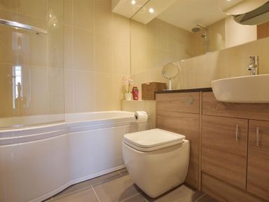 A bathroom with a bathtub toilet sink and wooden cabinets at Gwelfor Newport in Newport Pembrokeshire