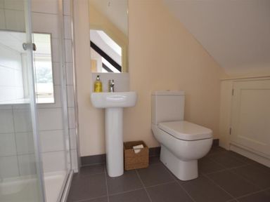 A bathroom with a shower enclosure sink toilet and a wicker basket at Gwelfor Newport in Newport Pembrokeshire