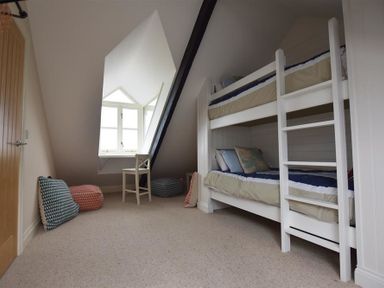 A bedroom with bunk beds a chair and window at Gwelfor Newport