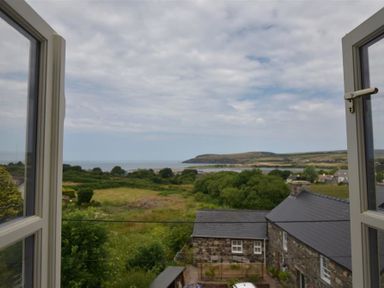 A view through open windows showing green fields trees stone houses and hills near the coast at Gwelfor Newport in Newport Pembrokeshire