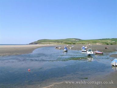 A tidal estuary with boats on mudflats and green hills in the background at Gwelfor Newport in Newport Pembrokeshire
