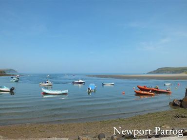 Boats floating on water near a sandy shore at Newport Parrog