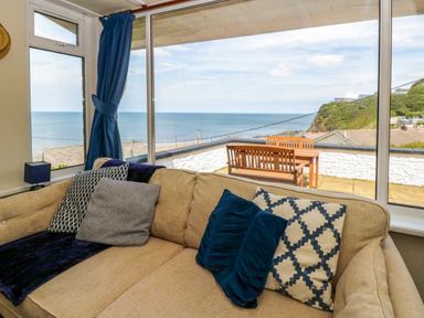 A living room with a view of the sea and outdoor seating at Delyn Aur, Tresaith, Ceredigion