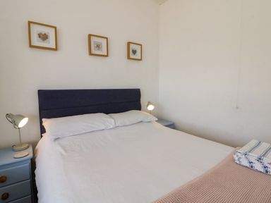 A bedroom with a bed and bedside lamp at Delyn Aur, Tresaith, Ceredigion