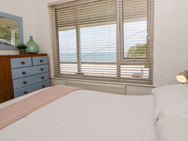 A bedroom with a window and dresser at Delyn Aur Tresaith, Ceredigion