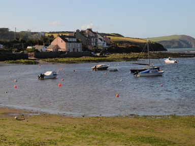 A small harbor with boats moored in water near houses and hills at Neverndale Newport Pembrokeshire