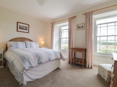 A bedroom with a bed bedside tables windows and curtains at Neverndale in Newport Pembrokeshire