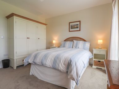 A bedroom with a double bed bedside tables lamps and a wardrobe at Neverndale Newport Pembrokeshire