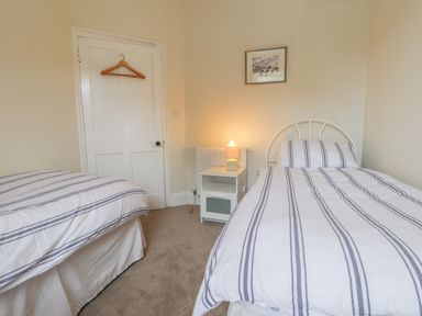 A bedroom with two single beds a nightstand with a lamp and a door with a hanger at Neverndale in Newport Pembrokeshire