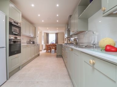 A kitchen with green cabinets and appliances leading to a dining area at Neverndale in Newport Pembrokeshire
