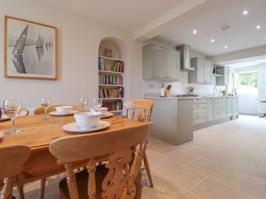 A kitchen and dining area with a wooden table and chairs and built-in cabinets at Neverndale in Newport Pembrokeshire