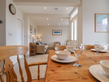 A dining table set with bowls and glasses in a room with a living area at Neverndale Newport Pembrokeshire