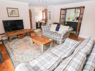 A living room with plaid sofas wooden coffee table and television at Mill Barn Denant in Haverfordwest Pembrokeshire