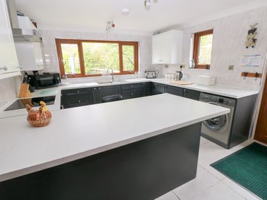 A kitchen with white countertops black cabinets a ceramic hen decoration and a washing machine at Mill Barn Denant in Haverfordwest Pembrokeshire