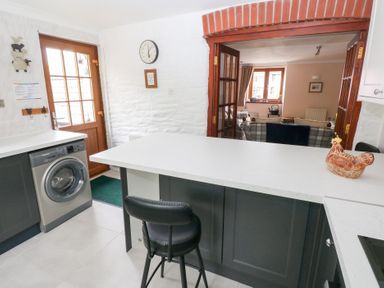 A kitchen with a washing machine black chair and a ceramic chicken on the counter at Mill Barn Denant in Haverfordwest Pembrokeshire