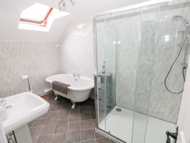 A bathroom with a clawfoot bathtub a glass-enclosed shower and a pedestal sink at Mill Barn Denant in Haverfordwest Pembrokeshire