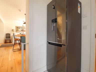 A kitchen area with a silver refrigerator and wooden flooring at Ty Cerrig in Newport Pembrokeshire
