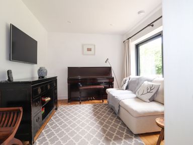 A living room with a piano a sofa and a television at Ty Cerrig in Newport Pembrokeshire