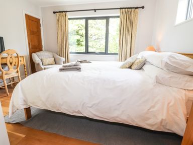 A bedroom with a bed and folded towels by a window with patterned curtains at Ty Cerrig Newport Pembrokeshire