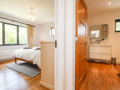 A bedroom with a bed and window next to a bathroom with a sink and mirror at Ty Cerrig in Newport Pembrokeshire
