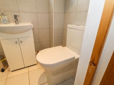 A bathroom with a white toilet and a white sink with cabinet and a bottle of hand soap at Ty Cerrig in Newport Pembrokeshire