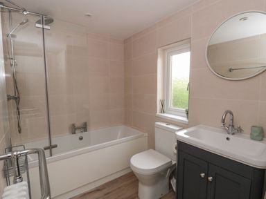 A bathroom with a shower, bath, toilet, and sink at Little Barn Cottage, Dinas Cross, Pembrokeshire