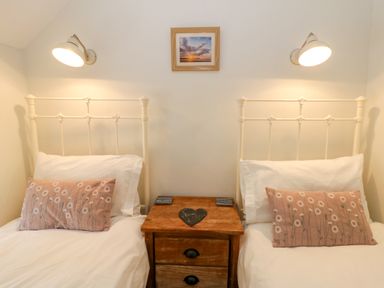 Two beds with pillows and a nightstand at Little Barn Cottage Dinas Cross, Pembrokeshire