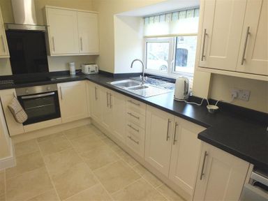 A kitchen with white cabinets black countertops a stainless steel oven sink toaster and kettle at Tremynydd Fawr in St Davids Pembrokeshire