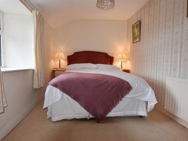 A bedroom with a double bed between two bedside tables with lamps at Tremynydd Fawr in St Davids Pembrokeshire
