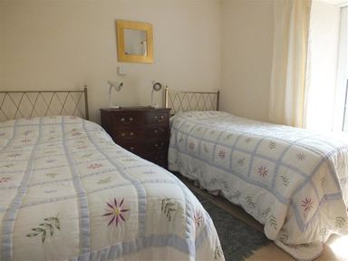 A bedroom with two single beds a wooden chest of drawers and a wall mirror at Tremynydd Fawr in St Davids Pembrokeshire