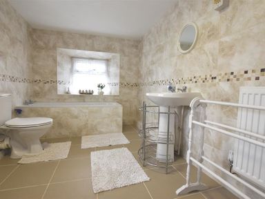 A bathroom with a toilet bathtub sink mirror and radiator at Tremynydd Fawr in St Davids Pembrokeshire