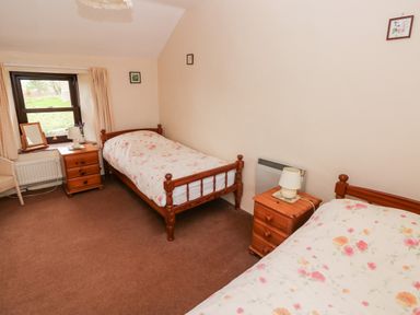 A bedroom with two single beds and wooden nightstands with lamps at Ty Canol in Mathry Pembrokeshire