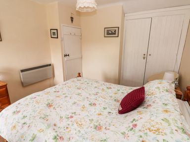 A bedroom with a floral bedspread and a red pillow on the bed at Ty Canol in Mathry Pembrokeshire