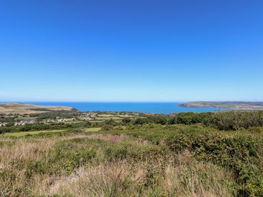 A coastal landscape with fields bushes and a small village near the sea at Ty Canol in Mathry Pembrokeshire
