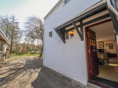 The exterior of a house with an open door showing a dining area inside at Meadowlands in Dinas Cross Pembrokeshire