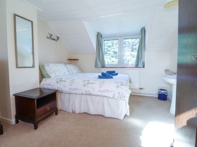 A bedroom with a double bed nightstand mirror window and sink at Meadowlands in Dinas Cross Pembrokeshire