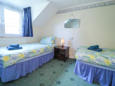 A bedroom with two single beds nightstand with lamp and window at Meadowlands in Dinas Cross Pembrokeshire