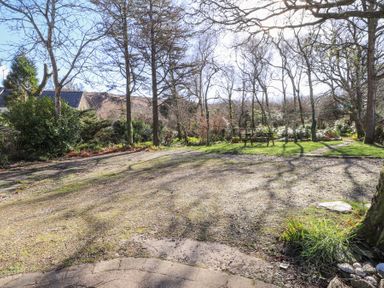 An outdoor garden area with trees a picnic table and a gravel pathway at Meadowlands in Dinas Cross Pembrokeshire