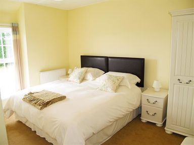 A bedroom with a double bed two pillows bedside tables and a wardrobe at Sarnau in Efailwen Carmarthenshire