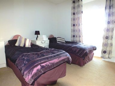 A bedroom with two single beds a nightstand with a lamp and towels and curtains with polka dots at Sarnau in Efailwen Carmarthenshire