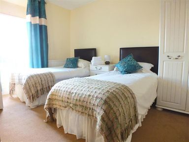 A bedroom with two single beds a bedside table with lamp and stacked towels and a wardrobe at Sarnau in Efailwen Carmarthenshire