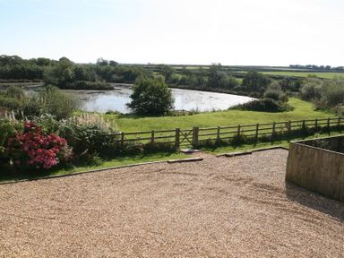 A gravel driveway with a wooden fence and a pond surrounded by greenery at Sarnau in Efailwen Carmarthenshire