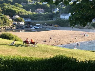 A beach with people on sand and in water with houses and trees in background at Beach Retreat Aberporth