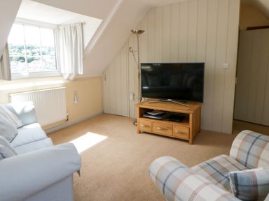 A living room with a television on a stand at Beach Retreat in Aberporth