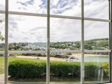 A view of a beach and houses through a window at Beach Retreat in Aberporth
